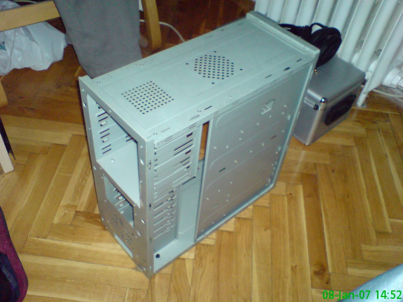 Stari sivi PC tower fotografiran odozgo, ventilacijski otvor vidljiv.